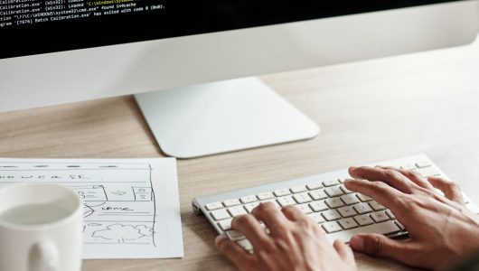 Closeup image of front end developer checking website hand-drawn website wireframe when coding
